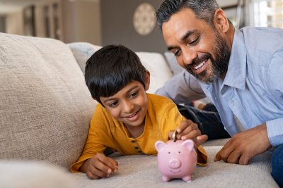 Father and son putting coin into piggy bank